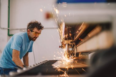 Ağır sanayi içinde. Modern bir fabrikada CNC makinesinde çalışan bir adam. Seçici odak