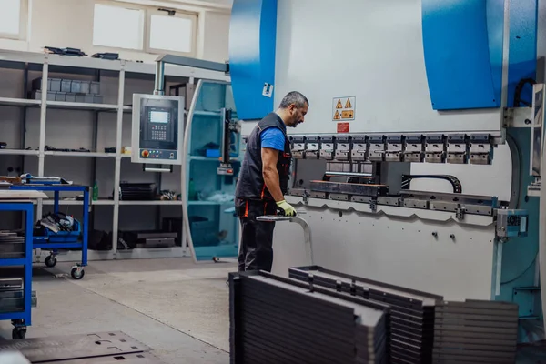 A smart factory worker or engineer makes machines in a production workshop. The concept of industry and engineering. Selective focus — Foto Stock