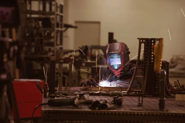 Saldatore di industria pesante professionale che lavora all'interno della fabbrica, indossa il casco e inizia la saldatura. Focus selettivo — Foto Stock