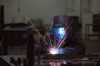 Professional Heavy Industry Welder Working Inside factory, Wears Helmet and Starts Welding. Selective Focus