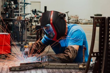 İçerideki fabrikada çalışan Profesyonel Ağır Sanayi Kaynakçısı, Kask Giyiyor ve Kaynak Yapmaya Başlıyor. Seçici Odaklanma