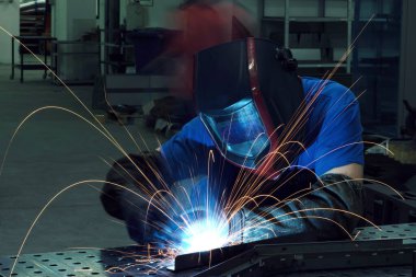 Professional Heavy Industry Welder Working Inside factory, Wears Helmet and Starts Welding. Selective Focus