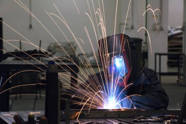 Professional Heavy Industry Welder Working Inside factory, Wears Helmet and Starts Welding. Selective Focus