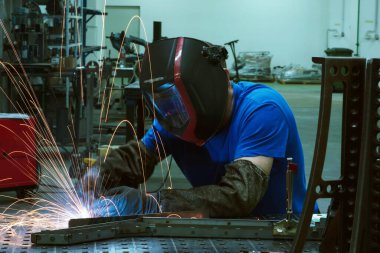 İçerideki fabrikada çalışan Profesyonel Ağır Sanayi Kaynakçısı, Kask Giyiyor ve Kaynak Yapmaya Başlıyor. Seçici Odaklanma