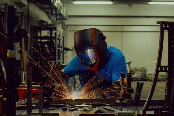 Soldador de indústria pesada profissional que trabalha dentro da fábrica, usa capacete e inicia a soldagem. Foco seletivo — Fotografia de Stock