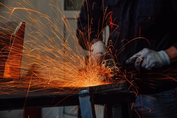 Heavy Industry Engineering Factory Interior with Industrial Worker Using Angle Grinder and Cutting a Metal Tube. Güvenlik Üniforması ve Sert Şapka Üretim Metal Yapıları Müteahhiti.