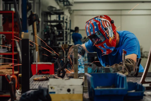 Soldador profesional de la industria pesada que trabaja dentro de la fábrica, usa casco y comienza la soldadura. Enfoque selectivo — Foto de Stock
