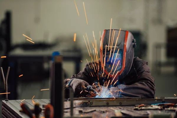 Soldador de indústria pesada profissional que trabalha dentro da fábrica, usa capacete e inicia a soldagem. Foco seletivo — Fotografia de Stock