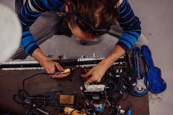 Industrial worker man soldering cables of manufacturing equipment in a factory. Selective focus — Photo