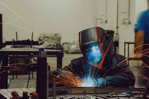 Professional Heavy Industry Welder Working Inside factory, Wears Helmet and Starts Welding. Selective Focus — Stok fotoğraf