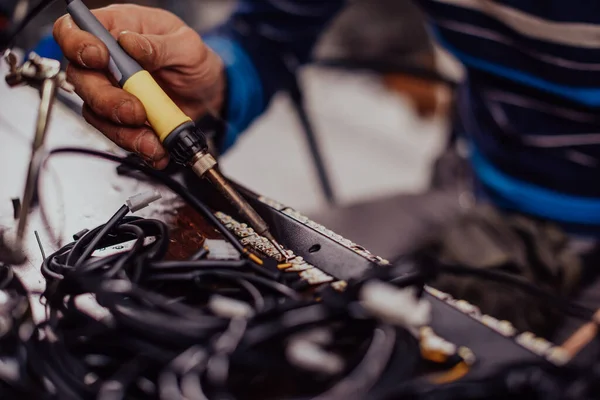 Industrial worker man soldering cables of manufacturing equipment in a factory. Selective focus — Stock fotografie