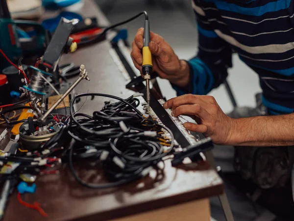 Industriële arbeider solderen kabels van productie-apparatuur in een fabriek. Selectieve focus — Stockfoto