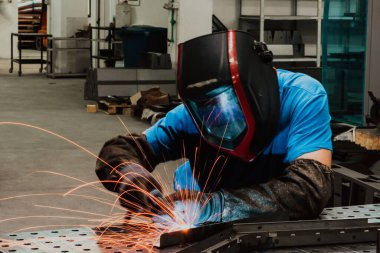 Professional Heavy Industry Welder Working Inside factory, Wears Helmet and Starts Welding. Selective Focus