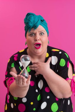 Büyük beden bir bayan portresi gülümseyen eller pembe arkaplanda izole edilmiş kum saati tutar..