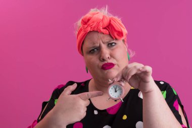 Büyük beden bir bayan portresi gülümseyen eller pembe arkaplanda izole edilmiş kum saati tutar..