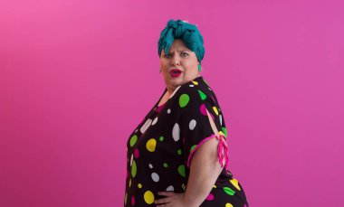 Artı, modaya uygun makyajlı seksi model kadın, stüdyoda pembe arka planda poz veren siyah kısa elbiseli şık sarışın..