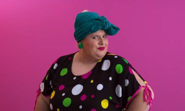 Artı, modaya uygun makyajlı seksi model kadın, stüdyoda pembe arka planda poz veren siyah kısa elbiseli şık sarışın..