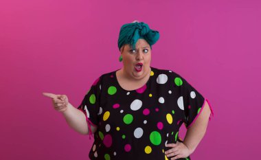 Artı, modaya uygun makyajlı seksi model kadın, stüdyoda pembe arka planda poz veren siyah kısa elbiseli şık sarışın..