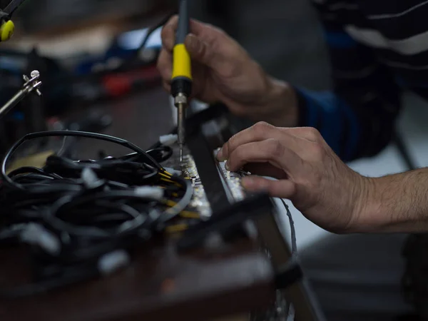 Industrial worker man soldering cables of manufacturing equipment in a factory. Selective focus — 스톡 사진