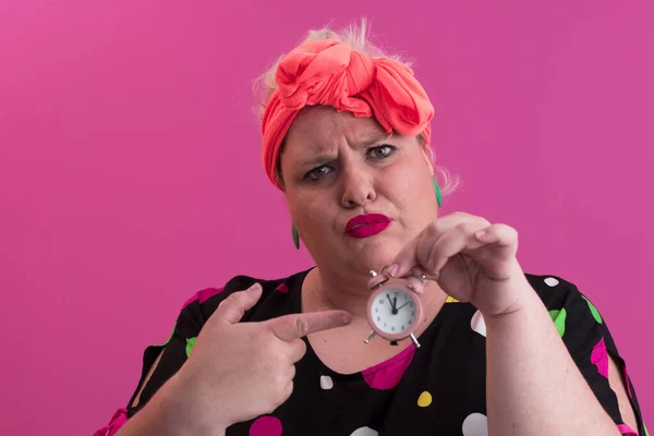 Portret van plus size jonge dame glimlachende handen houdt zand klok geïsoleerd op roze kleur achtergrond. — Stockfoto