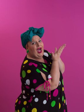 Artı, modaya uygun makyajlı seksi model kadın, stüdyoda pembe arka planda poz veren siyah kısa elbiseli şık sarışın..