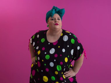 Artı, modaya uygun makyajlı seksi model kadın, stüdyoda pembe arka planda poz veren siyah kısa elbiseli şık sarışın..