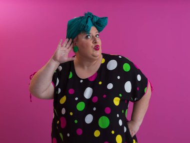 Artı, modaya uygun makyajlı seksi model kadın, stüdyoda pembe arka planda poz veren siyah kısa elbiseli şık sarışın..