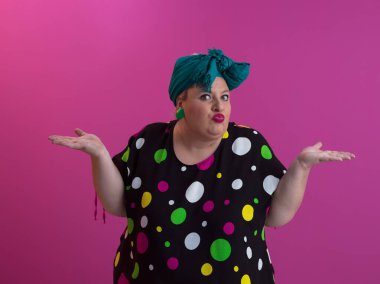 Artı, modaya uygun makyajlı seksi model kadın, stüdyoda pembe arka planda poz veren siyah kısa elbiseli şık sarışın..