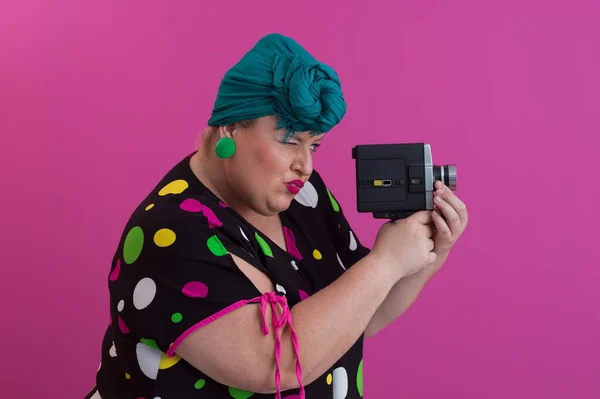 Más tamaño sonriente mujer con expresión de cara emocional divertida con cámara vintage en vestido aislado sobre fondo rosa, viajero de vacaciones, estilo de moda de verano, turista emocionado. — Foto de Stock