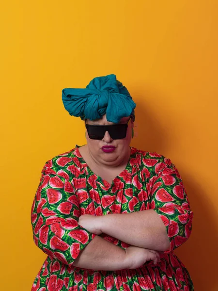Funny plus size sexy model woman with trendy sunglasses, fashionable overweight blonde in colorful dress posing at the yellow background in studio. — Fotografia de Stock