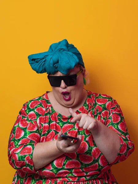 Blond plus size vrouw hebben gesprek praten met de smartphone over gele achtergrond glimlachen met een idee of vraag wijzend vinger met gelukkig gezicht, nummer een — Stockfoto