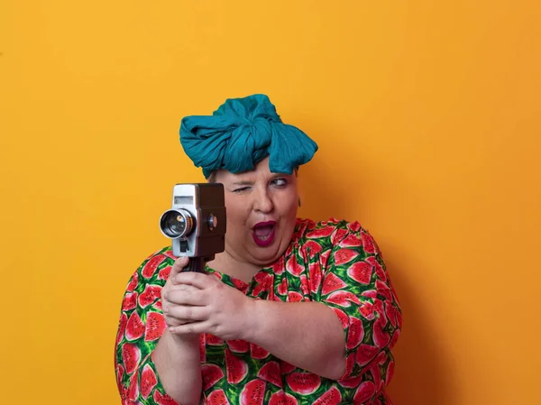 Plus size smiling woman with funny emotional face expression with vintage camera in dress isolated on yellow background, traveler on vacation, summer fashion style, excited tourist. — Stok fotoğraf
