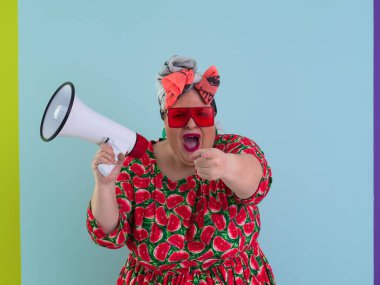 Cyan arkaplan stüdyo resminde izole edilmiş komik ve cüsseli bir kadın. Bir megafonda çığlık atmak. İnsanlar yaşam tarzı kavramını hisseder. Kopyalama alanı oluştur. 