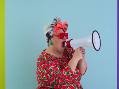 Cyan arkaplan stüdyo resminde izole edilmiş komik ve cüsseli bir kadın. Bir megafonda çığlık atmak. İnsanlar yaşam tarzı kavramını hisseder. Kopyalama alanı oluştur. 