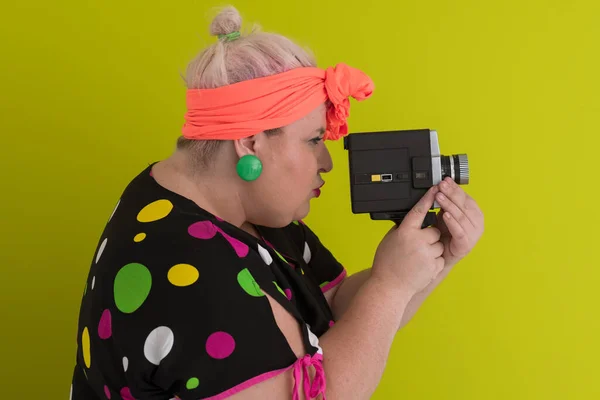 Plus size smiling woman with funny emotional face expression with vintage camera in dress isolated on green background, traveler on vacation, summer fashion style, excited tourist. — Zdjęcie stockowe