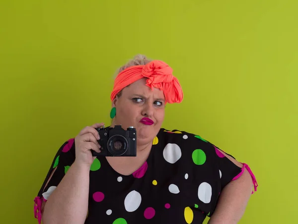 Plus size smiling woman with funny emotional face expression with vintage camera in dress isolated on green background, traveler on vacation, summer fashion style, excited tourist. — Fotografia de Stock