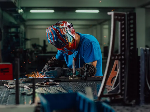 İçerideki fabrikada çalışan Profesyonel Ağır Sanayi Kaynakçısı, Kask Giyiyor ve Kaynak Yapmaya Başlıyor. Seçici Odaklanma — Stok fotoğraf
