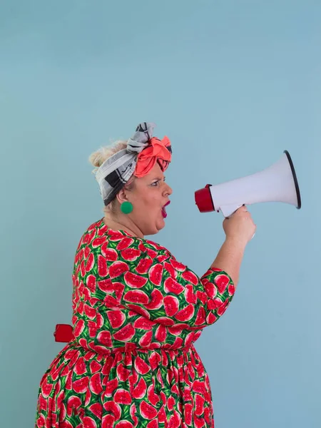 Cyan arkaplan stüdyo resminde izole edilmiş komik ve cüsseli bir kadın. Bir megafonda çığlık atmak. İnsanlar yaşam tarzı kavramını hisseder. Kopyalama alanı oluştur. 