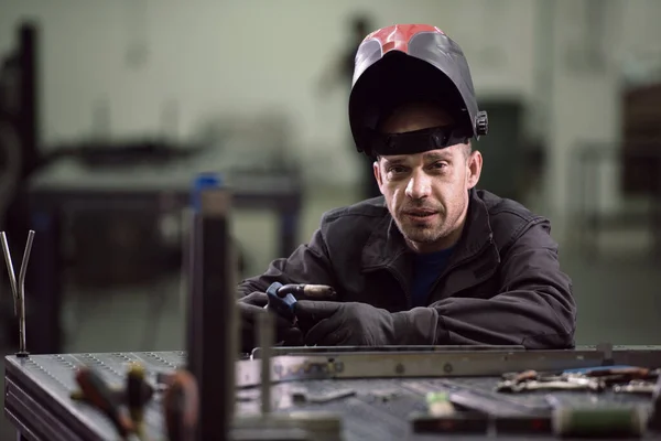 Portrait of Young Professional Heavy Industry Engineer. Worker Wearing Safety Vest and Hardhat Smiling on Camera. In the Background Unfocused Large Industrial Factory — Stockfoto