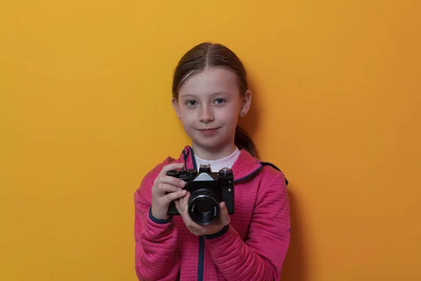 Menina fotógrafo isolado no fundo amarelo sorrindo tirar fotos com uma câmera vintage retro. — Fotografia de Stock