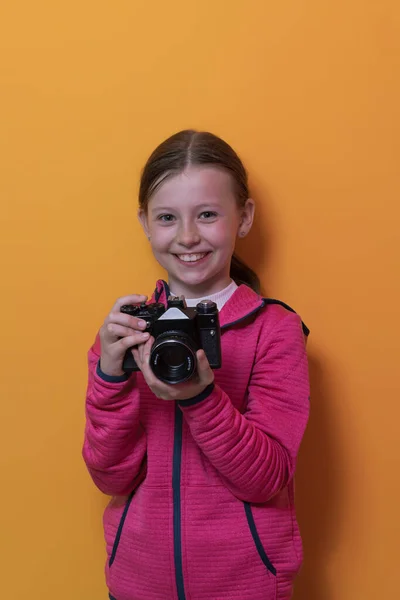 Menina fotógrafo isolado no fundo amarelo sorrindo tirar fotos com uma câmera vintage retro. — Fotografia de Stock