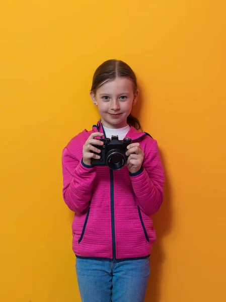 女の子の写真家は、レトロなヴィンテージカメラで写真を撮る黄色の背景笑顔に隔離. — ストック写真