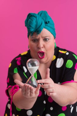 Büyük beden bir bayan portresi gülümseyen eller pembe arkaplanda izole edilmiş kum saati tutar..