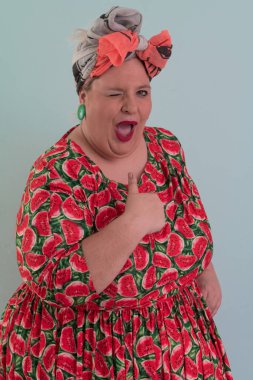 Artı, modaya uygun makyajlı seksi manken kadın, renkli elbiseli şık sarışın stüdyo ortamında veya açık mavi arka planda poz veren..