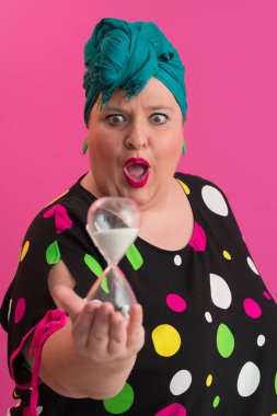 Büyük beden bir bayan portresi gülümseyen eller pembe arkaplanda izole edilmiş kum saati tutar..