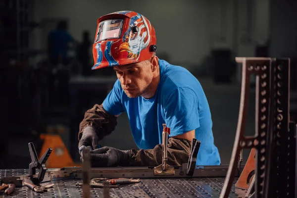 Soldador profesional de la industria pesada que trabaja dentro de la fábrica, usa casco y comienza la soldadura. Enfoque selectivo —  Fotos de Stock
