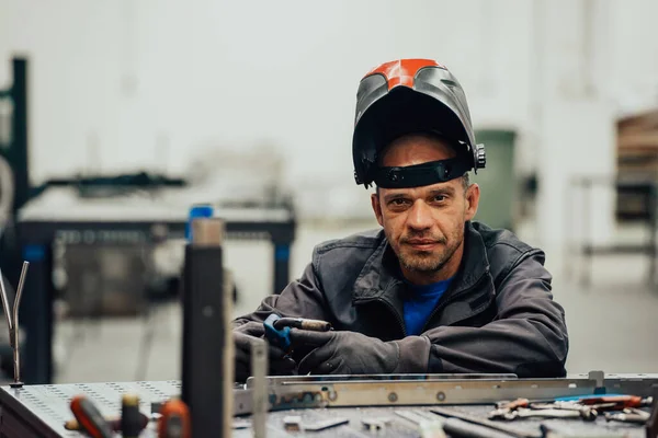 Soldador de indústria pesada profissional que trabalha dentro da fábrica, usa capacete e inicia a soldagem. Foco seletivo — Fotografia de Stock