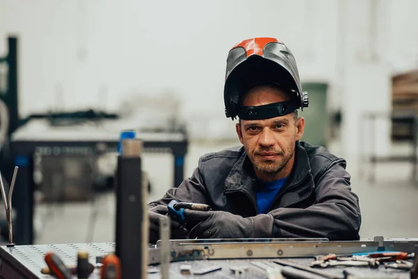 Soldador profesional de la industria pesada que trabaja dentro de la fábrica, usa casco y comienza la soldadura. Enfoque selectivo —  Fotos de Stock