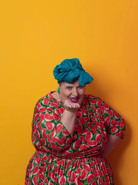 Funny plus size sexy model woman with trendy makeup, fashionable overweight blonde in colorful dress posing at the yellow background in studio. — Fotografia de Stock