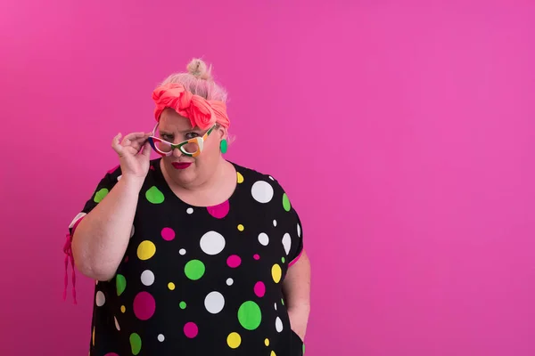 Glad Plus storlek kvinna bär glasögon ler mot kameran stående över rosa bakgrund. Glada Millennial Kvinna i glasögon Posing In Studio. — Stockfoto